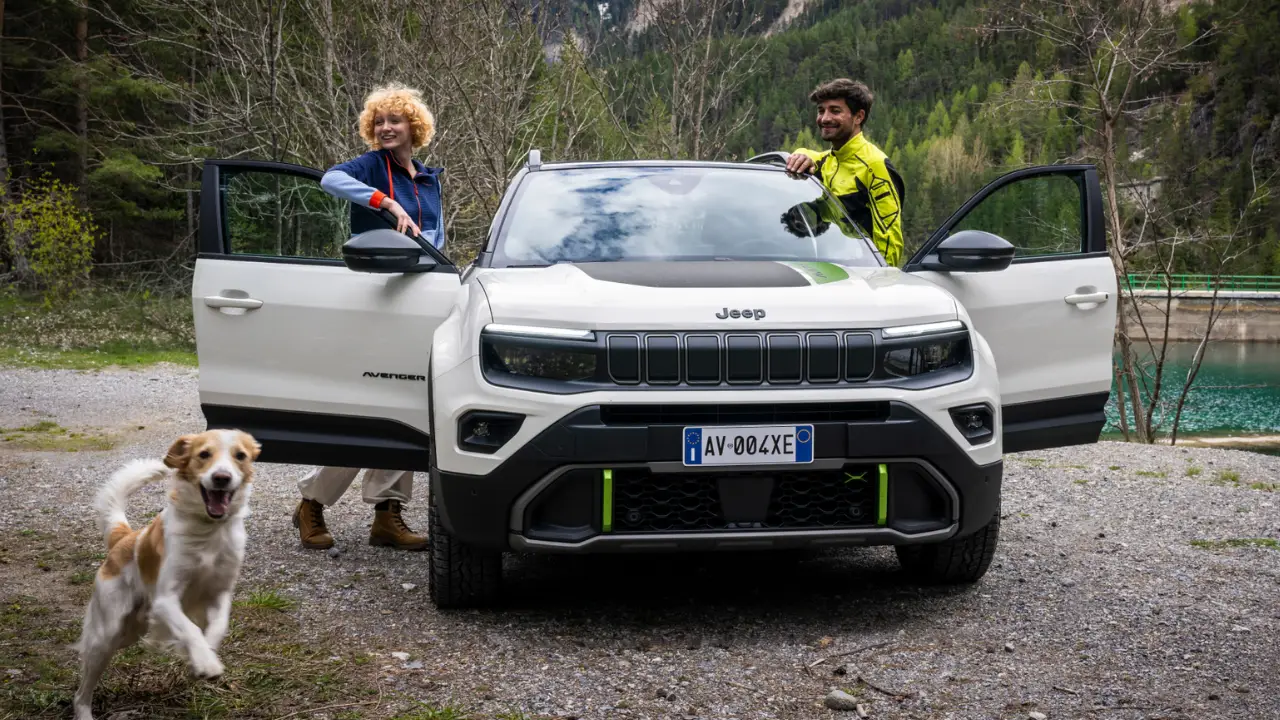 Jeep Avenger 4xe bianca con un uomo e una donna ai lati e un cane in primo piano