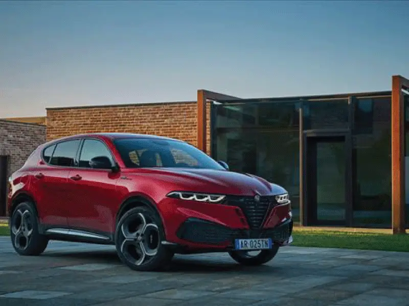 Nuova Alfa Romeo Tonale rossa parcheggiata fuori una casa moderna con vetrate